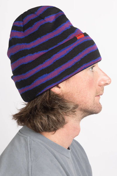 Person wearing a striped beanie with black, blue, and red colors on a white background