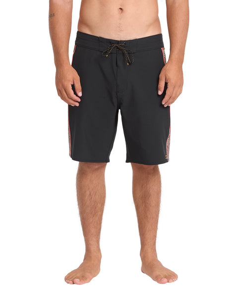 A man modeling black board shorts with a dark drawstring and subtle orange side stripes, shown from the waist down against a plain white background.